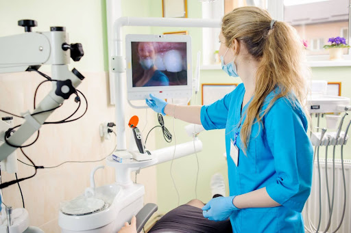 A female dentist analyzes the live intraoral picture of the patient’s teeth.