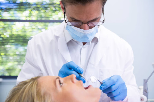 A close up of a dentist examining a woman