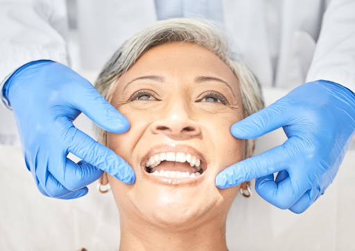 An older woman is at the dentist getting her teeth examined.